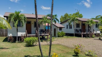 A two-story house with a porch, surrounded by palm trees and a well-maintained lawn.