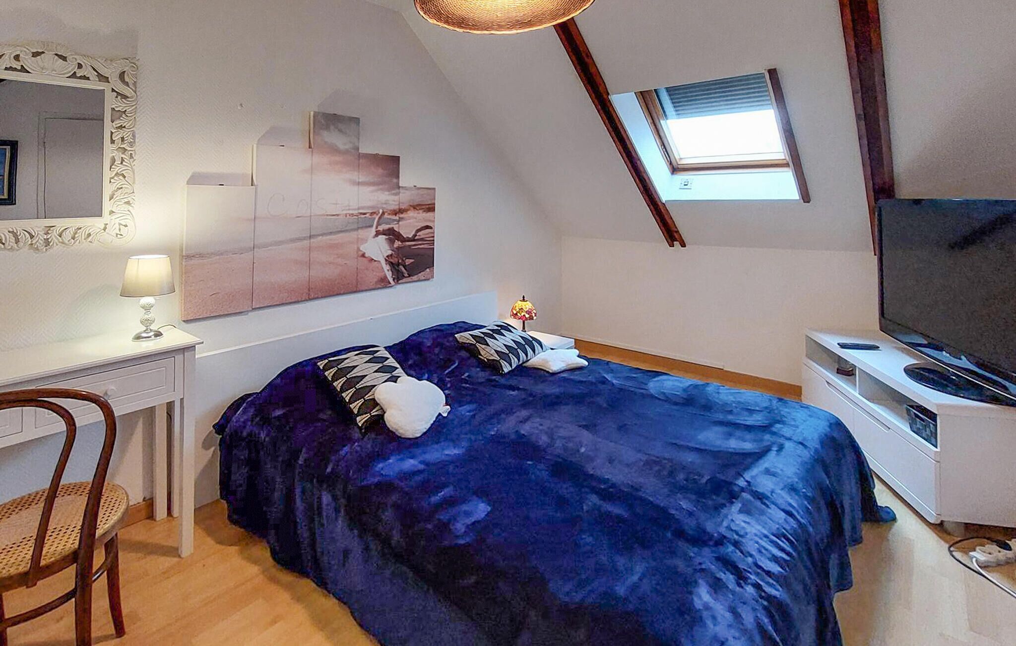 Une chambre à coucher avec un lit, un bureau, une chaise, un téléviseur et une fenêtre.