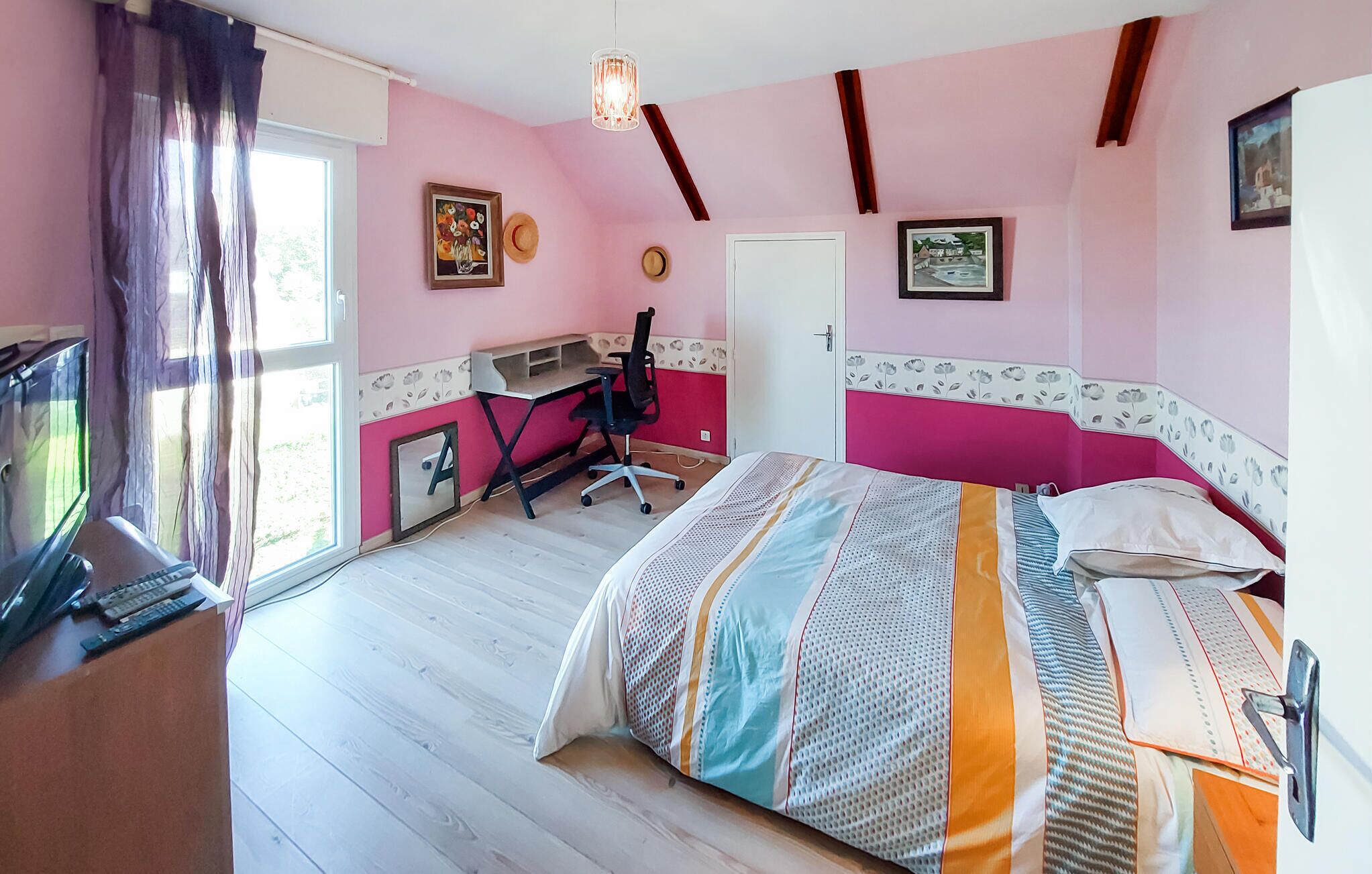 Ein Schlafzimmer mit Bett, Schreibtisch, Stuhl und Fernseher.