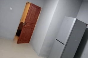 Compact room with a kitchenette area and a single door leading to another space.