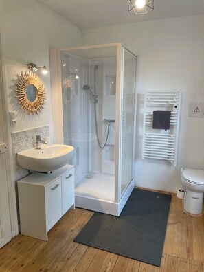 A modern bathroom with a glass-enclosed shower, a white sink, and a toilet.