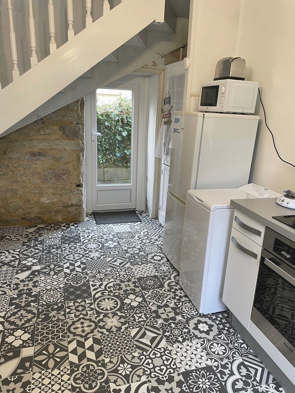 A kitchen with patterned tiles, a white refrigerator, a microwave, and a dishwasher.