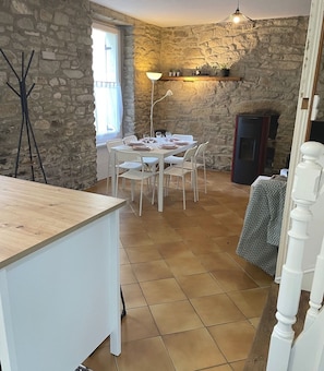 A dining area with a stone wall, a wooden table set for four, and a modern pendant light.
