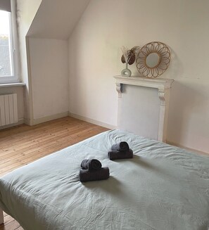 A room with a bed, a white fireplace, and a window.