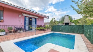 A swimming pool with a tiled edge, a pink building with a blue door, and a green hedge. - Cozy home in Sant Miquel de Fluvià (Sant Miquel de Fluvià)