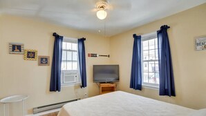 Un dormitorio con una cama, televisión y una mesita.
