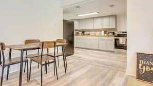 Una cocina moderna con armarios blancos, una mesa de comedor de madera con sillas y un letrero que dice "THANK YOU".