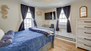 A bedroom with a bed, a dresser, a TV, and a heater.