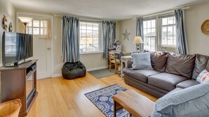 A cozy living room with a sofa, a TV, and a dining area with a table and chairs.