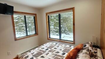 A bedroom with a large bed, two windows, and a ceiling light.