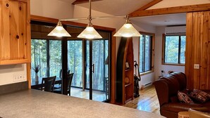 A kitchen with a large island, wooden beams, and pendant lighting. - Riverside Cabin Near Torch Lake – Kayaks Included! (Rapid City)