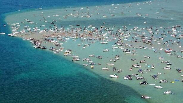 An aerial view of a beach crowded with boats and people. - Riverside Cabin Near Torch Lake – Kayaks Included! (Rapid City)
