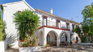 A white building with red accents, featuring a balcony and arched windows. - Luxurious home in Santaella (Santaella)