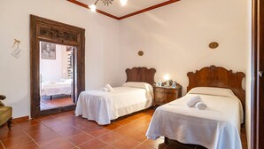 A hotel room with two beds, a wooden headboard, a nightstand, and a mirror with a decorative frame. - Luxurious home in Santaella (Santaella)