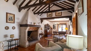 A traditional living room with exposed wooden beams, a fireplace, and classic furniture. - Luxurious home in Santaella (Santaella)