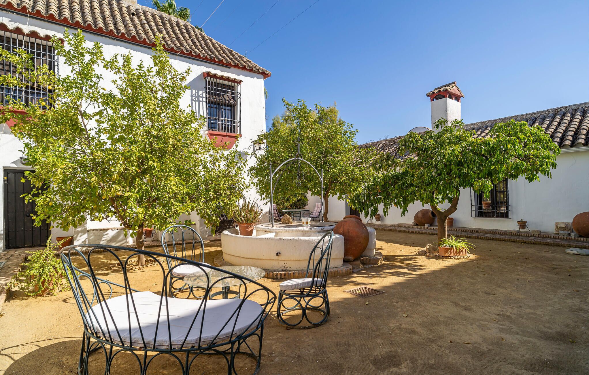A courtyard with a white building, a fountain, and outdoor seating.