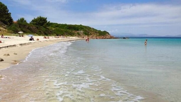 A beach with clear shallow waters, a sandy shore, and a few people. - Apartments La perla - Apartment with Balcony (Carloforte)