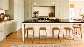 A kitchen with a central island, bar stools, pendant lights, and wooden flooring. - Luxury Golf Suncadia Retreat- Hot Tub + Sleeps 20 (Cle Elum)