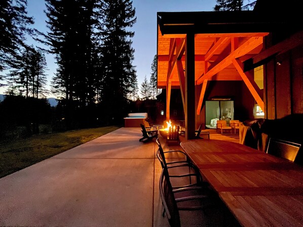 A modern outdoor patio area with a fire pit, seating, and a view of the interior of a building. - Experience Magical Holidays in Suncadia! 7BR Luxury Lodge w/ Hot Tub + Game Room (Cle Elum)
