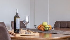Een eettafel met een fles wijn, een glas en een schaal fruit.
