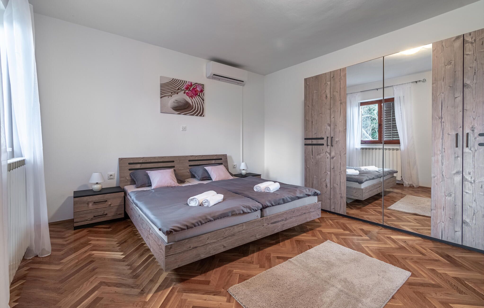 Une chambre à coucher avec un grand lit, une table de chevet, un miroir et une armoire.