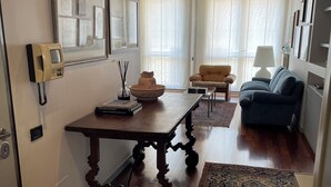 A living room with a wooden table, a sofa, a lamp, and a patterned rug. - Residence Clementina, 155sqm of charm in the historic center (Padova)