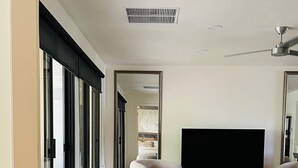 Un salon moderne doté d’un grand téléviseur à écran plat, d’un canapé bleu, d’un fauteuil noir et d’un ventilateur de plafond.