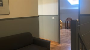 Un salon moderne avec un canapé foncé, un plancher en bois et un luminaire au plafond.
