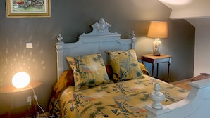 Une chambre à coucher avec un lit, une table de chevet, une lampe et un tableau accroché au mur.
