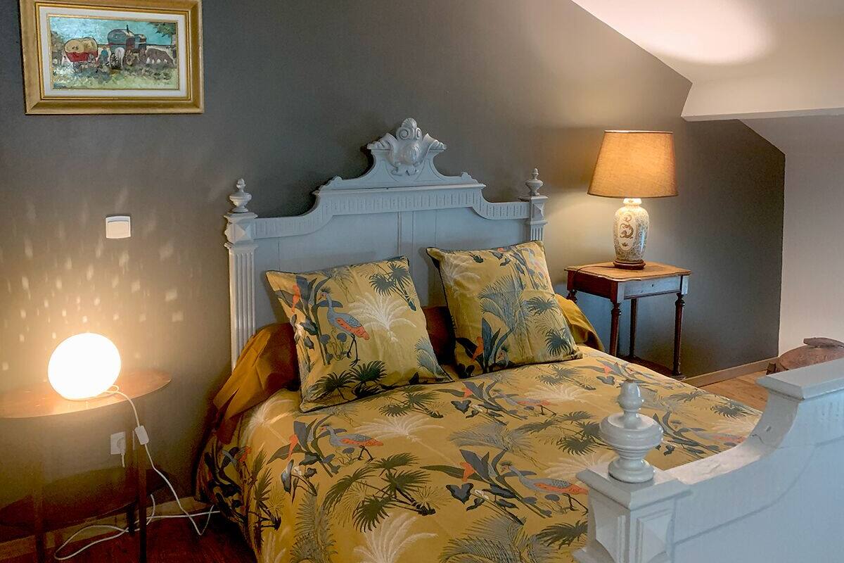 Une chambre à coucher avec un lit, une table de chevet, une lampe et un tableau accroché au mur.