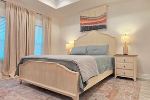 Ein Schlafzimmer mit einem hölzernen Bett, zwei Nachttischen mit Lampen, einem gemusterten Teppich und einer Wanddekoration.