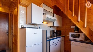 A compact kitchen with white cabinets, a built-in stove, and a microwave. - LA COCHETTE - JARRIER (JARRIER)