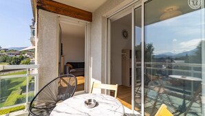 Un balcón con una mesa y sillas, un sofá y un ventanal corredera que da a una habitación.