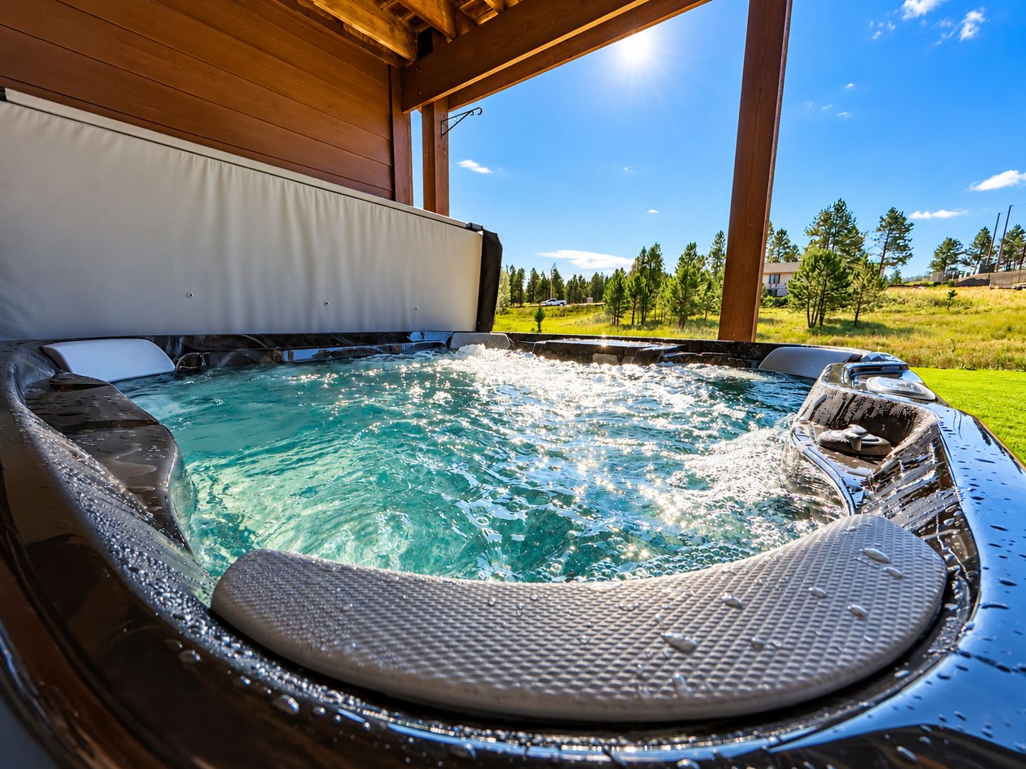 A hot tub with a view of a grassy landscape and trees.