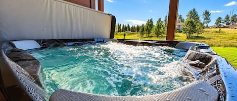 A hot tub with a view of a grassy landscape and trees.