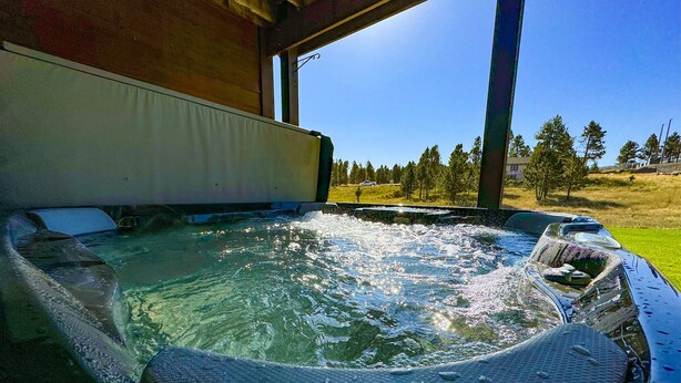 A hot tub with a view of a grassy field and trees. - Serene Golf Course Home Getaway with Hot Tub (Sturgis)