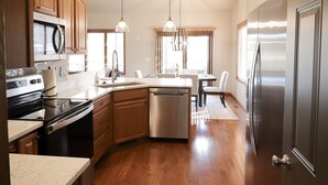 A modern kitchen with wooden cabinets, stainless steel appliances, and a central island. - Serene Golf Course Home Getaway with Hot Tub (Sturgis)