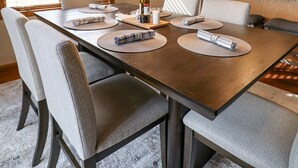 A dining area with a large wooden table, cushioned chairs, and a hanging pendant light. - Serene Golf Course Home Getaway with Hot Tub (Sturgis)