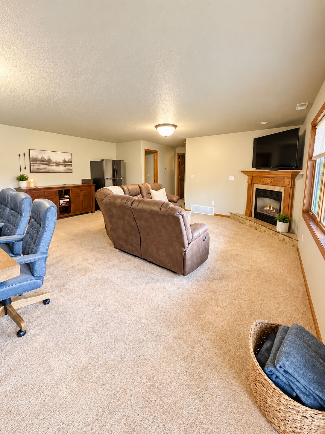 A living room with a brown sofa, a blue armchair, a television, and a fireplace.