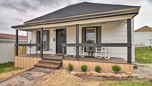 Einbungalow mit verdeckter Veranda, Eingangstür und einer kleinen Sitzgelegenheit mit Stühlen.