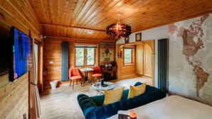 A cozy cabin interior with wooden walls, a large bed, a dining area, and a map on the wall.
