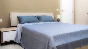 A bedroom with a bed, nightstand, lamp, and a door. - 76 Avenue Suite - Very close to the city center (Reggio Calabria)