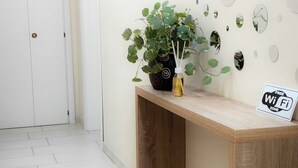 A room with a wooden desk, a potted plant, a "Free WiFi" sign, and a white door. - 76 Avenue Suite - Very close to the city center (Reggio Calabria)