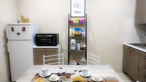 A compact kitchen with a microwave, refrigerator, and a shelf with snacks. - 76 Avenue Suite - Very close to the city center (Reggio Calabria)