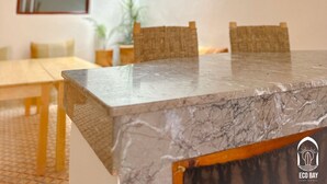 A modern kitchen with a marble countertop, hanging pendant lights, and a large window providing natural light. - Eco Bay hostel  (Aourir)
