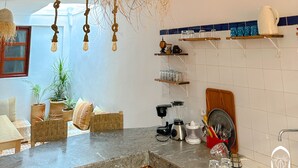 A kitchen with a hanging woven light fixture, a blender, and various kitchen items on shelves. - Eco Bay hostel  (Aourir)