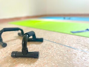 A pair of black exercise equipment on a speckled floor with a green mat in the background. - Eco Bay hostel  (Aourir)