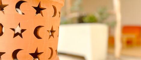 A terracotta pot with star and crescent cutouts, placed on a white pedestal.