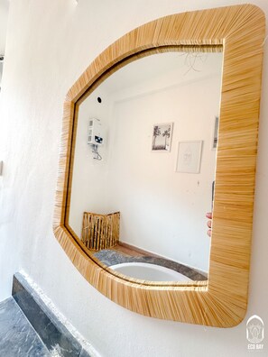 A bathroom with a large mirror, a towel rack, and a small framed picture on the wall. - Eco Bay hostel  (Aourir)
