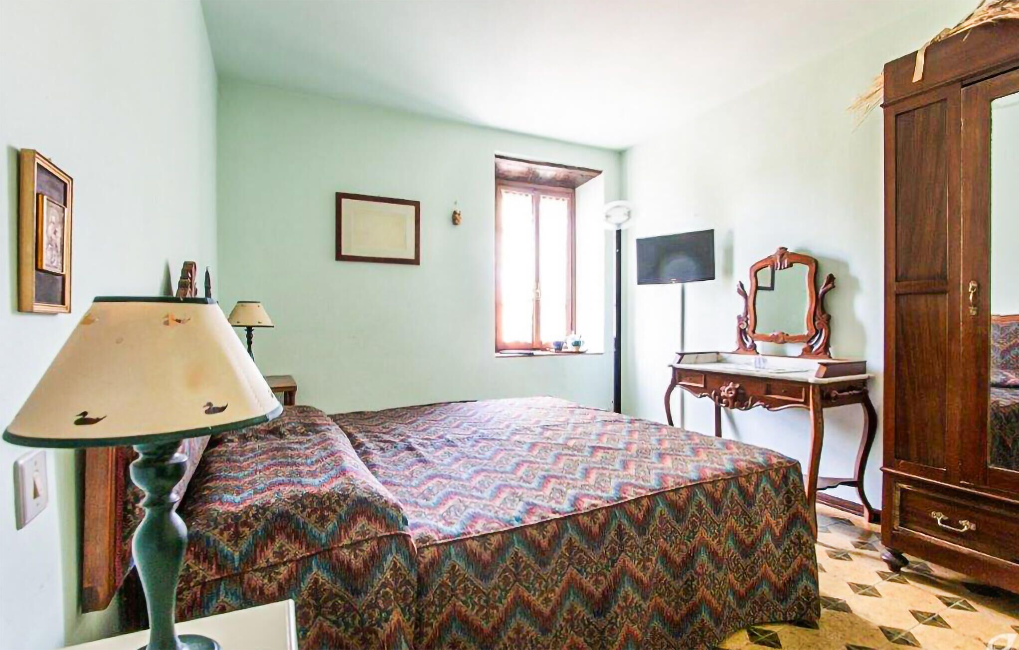 A room with a bed, a desk, a mirror, and a wardrobe.